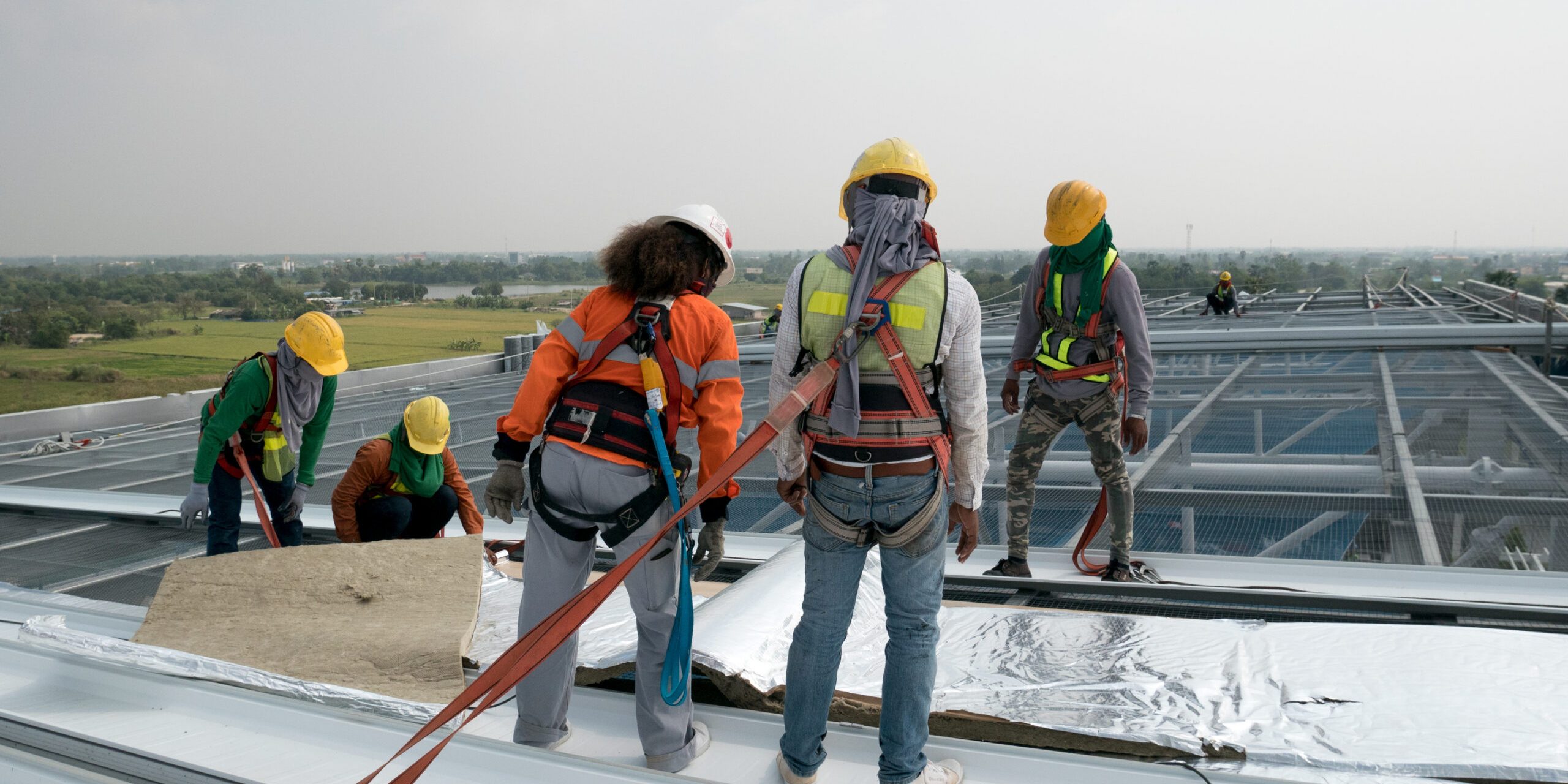 ConstructionWorkerWearingSafetyHarnessAndSafetyLineWorkingOn Commercial Roof Replacement Contractor